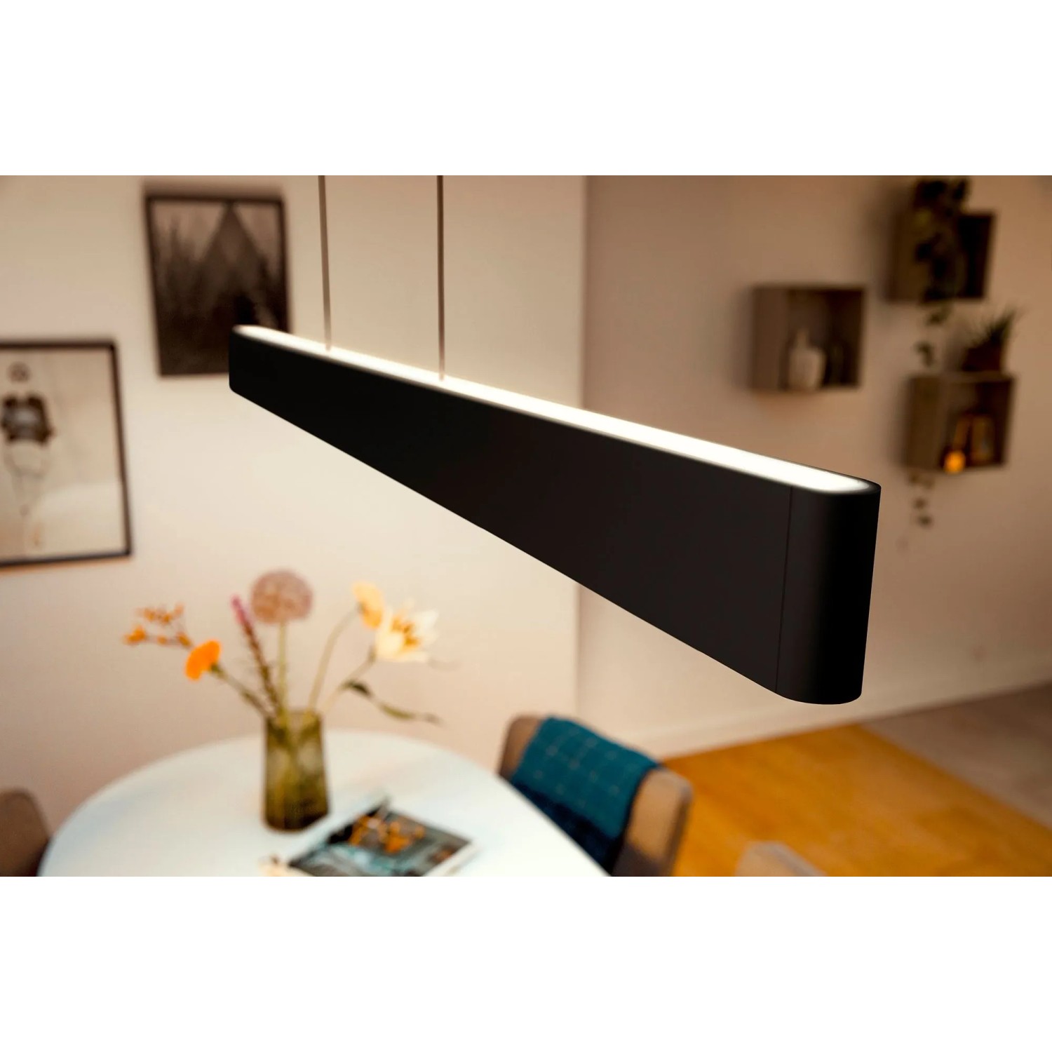 Moderne, schwarze Philips Hue LED-Pendelleuchte Ensis mit Farbwechsel über Esstisch.
