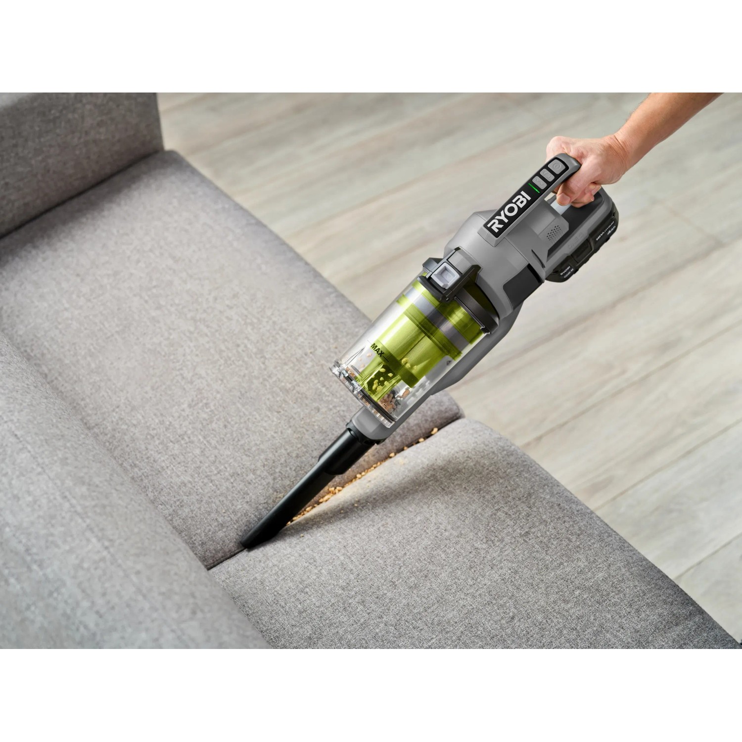 Ryobi Akku-Staubsauger RSVS18-0 One+ 18V in Aktion auf Sofa. Handstaubsauger für Möbelreinigung.