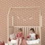 ESTAhome Vliestapete Terrakottarosa mit weißen Sternen im Kinderzimmer über einem Holzbett. Dekorative Tapete.