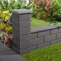 Anthrazitfarbene Gartenmauer aus Halbsteinen (25x20x25 cm) als Grundstückseinfassung.