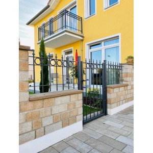 Eleo Zaun Belluno, pulverbeschichtet, 96 cm, vor gelbem Haus. Gartenzaun mit Kreisdekoren und Pinien-Spitzen.