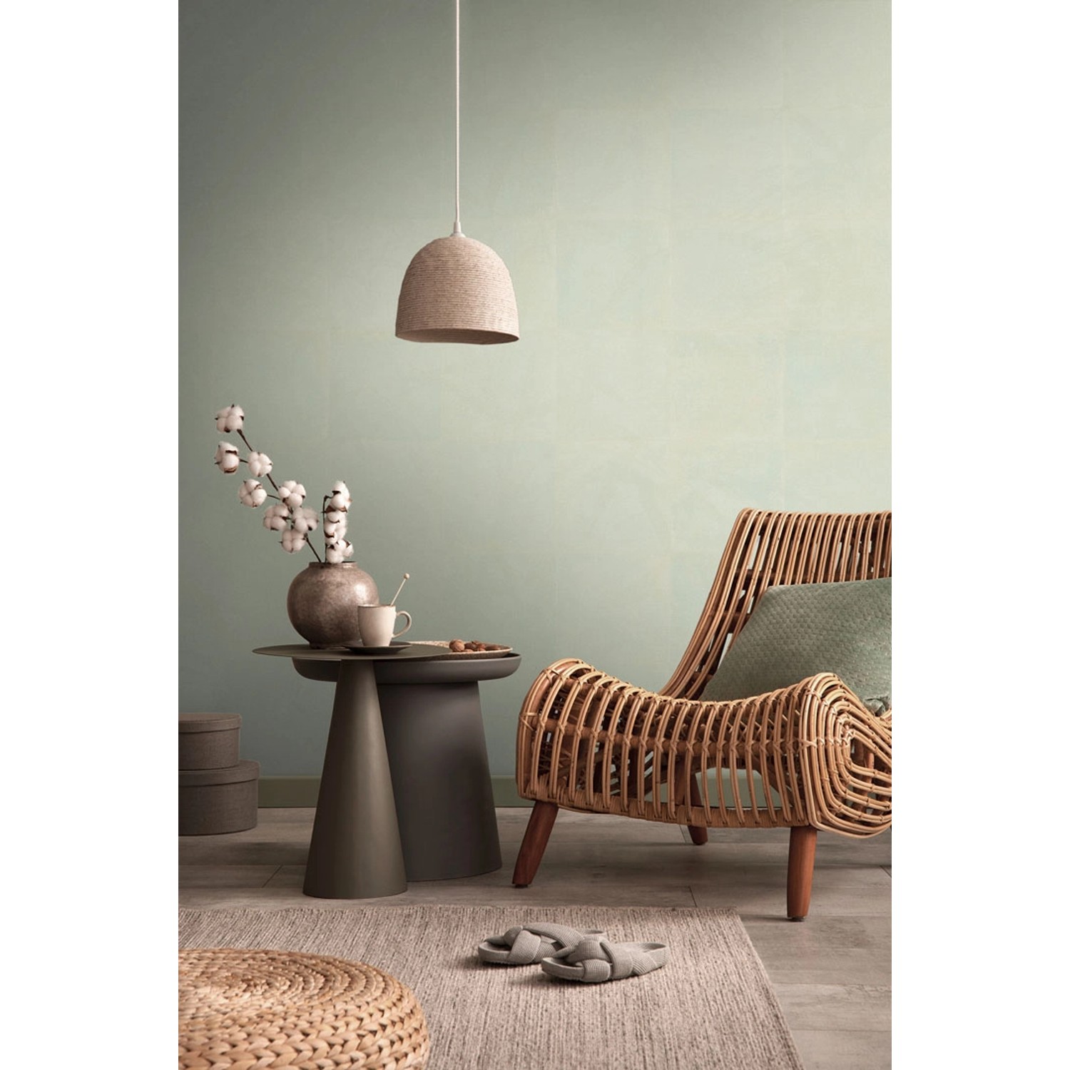 Wohnraum mit hellgrüner AS-Creation Vliestapete, Rattansessel und Beistelltisch.