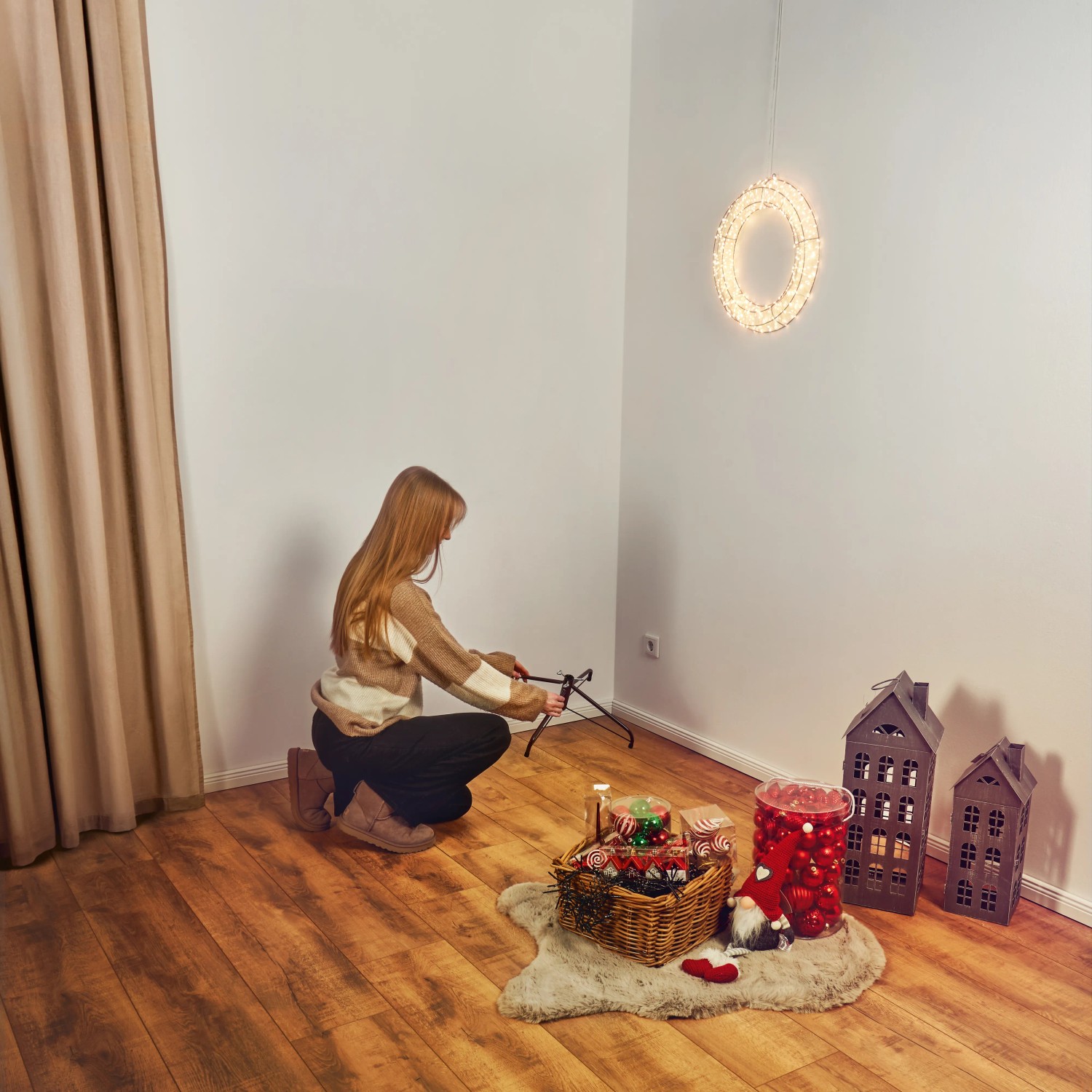 Frau baut grüne Kunsttanne Nagano (150 cm) auf. Weihnachtsdeko im Raum.