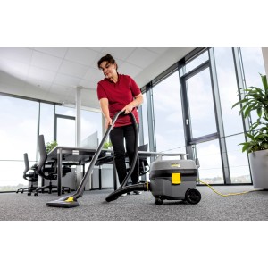 Frau saugt Büro mit Kärcher T 7/1 Classic ADV Trockensauger. Kompakter Gewerbesauger mit 7 l Behälter.