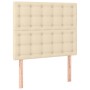 Cremefarbenes Boxspringbett mit gestepptem Kopfteil und Holzfüßen, Stoffbezug.