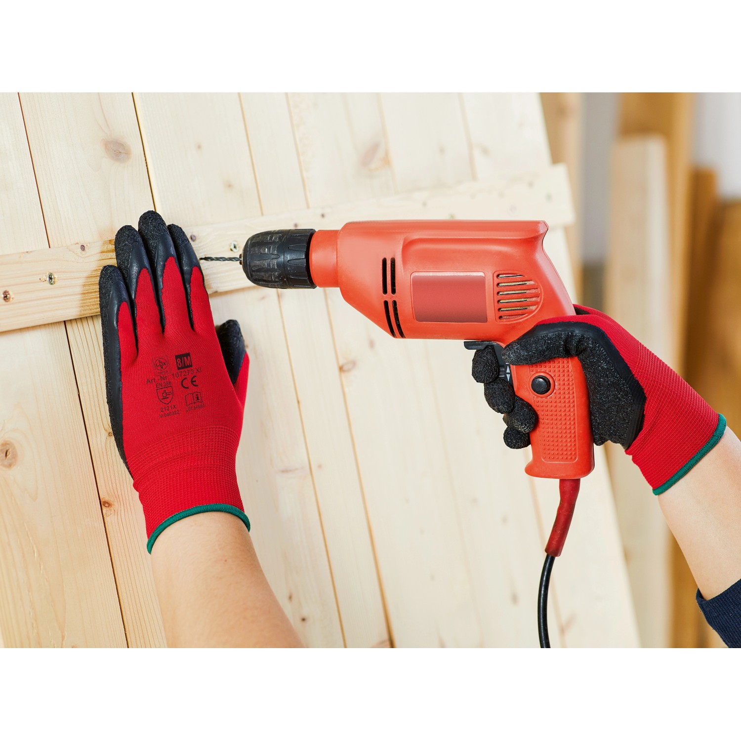 Hände mit roten Latex Arbeitshandschuhen (5er-Pack) beim Bohren in Holz. Größe 8.