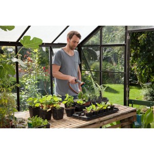 Mann bewässert Pflanzen mit Gardena Comfort Gartenbrause im Gewächshaus.