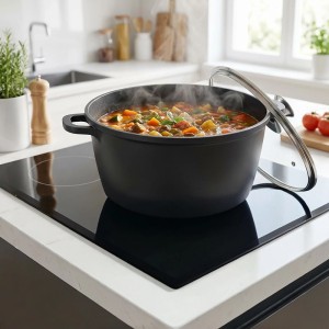 Schwarzer Relaxdays Suppentopf (28 cm) aus Aluguss mit Glasdeckel auf einem Induktionsherd.