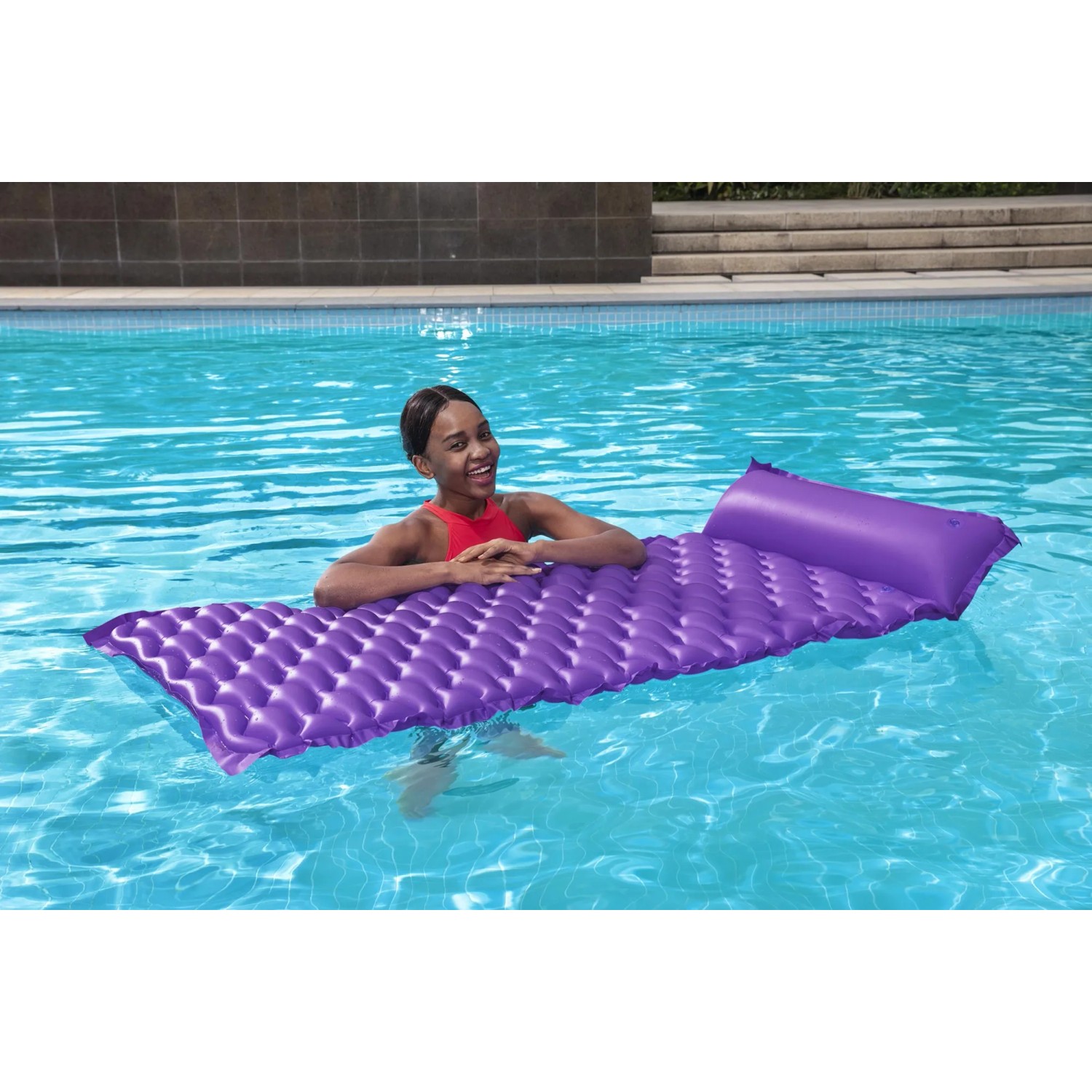 Frau entspannt auf lila Bestway Luftmatratze Float'n Roll (213x86cm) im Pool.