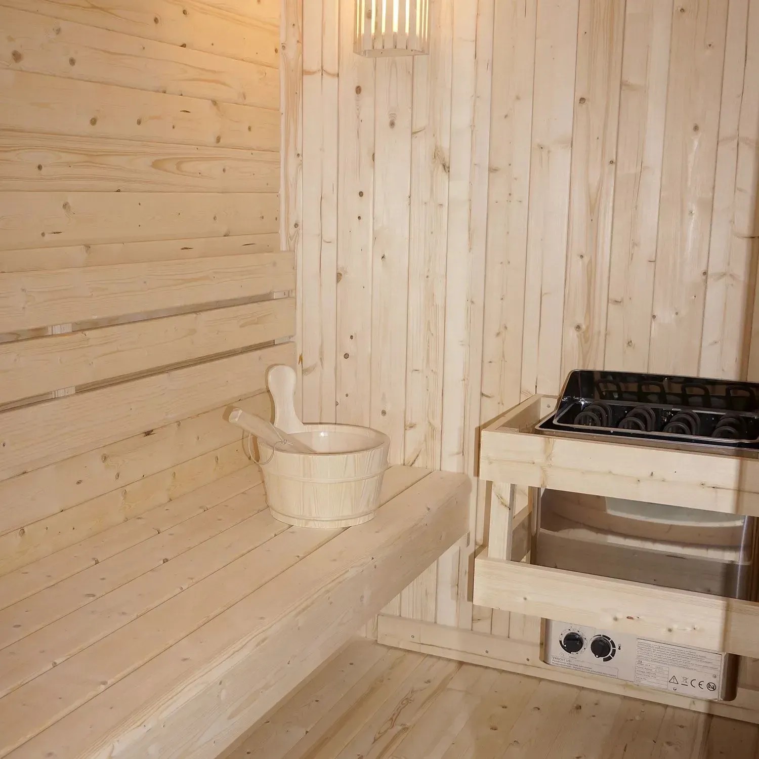 Innenansicht Artsauna Cube Fasssauna Nolvik XXL mit Ofen, Eimer und Holzwänden.