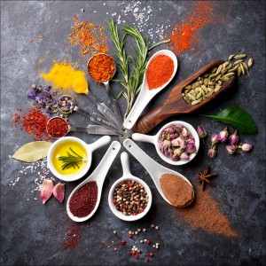 Pro-Art Glasbild Spicery I, 50x50 cm: Arrangement verschiedener Gewürze und Kräuter in Schalen und Löffeln.