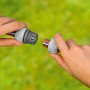 Gardena Reparator-Satz 13mm: Schlauchreparatur mit Kupplungen in Händen vor grünem Hintergrund.