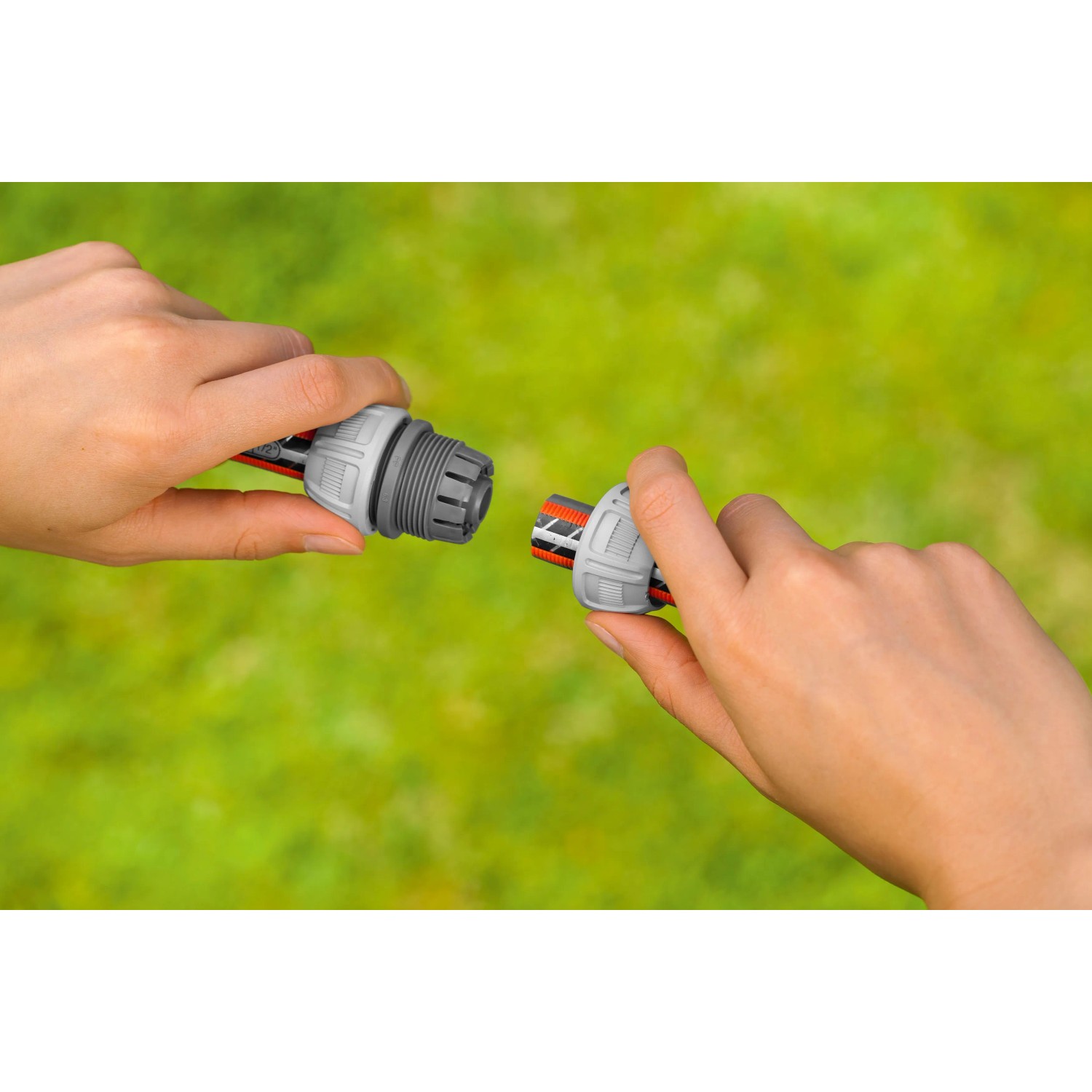 Gardena Reparator-Satz 13mm: Schlauchreparatur mit Kupplungen in Händen vor grünem Hintergrund.
