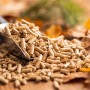 Haufen heller Holzpellets mit Metallschaufel auf Holzgrund. Heizfuxx Blue ENplus A1 Brennstoffe für Heizsysteme.