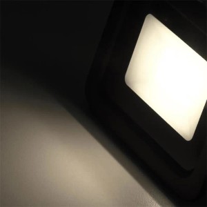 Schwarzer McShine LED Außenstrahler SLIM 10W mit neutralweißem Lichtstrahl auf dunklem Grund. IP66.
