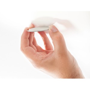 Hand hält Magnetpad (Ø 7 cm) zur Montage von Rauchwarnmeldern ohne Bohren.