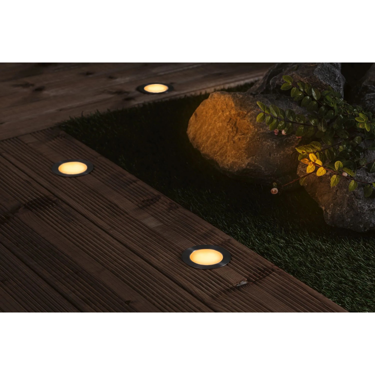 Paulmann LED Bodeneinbaustrahler Floor Plug & Shine 3er Set auf Holzterrasse mit Stein und Pflanzen.