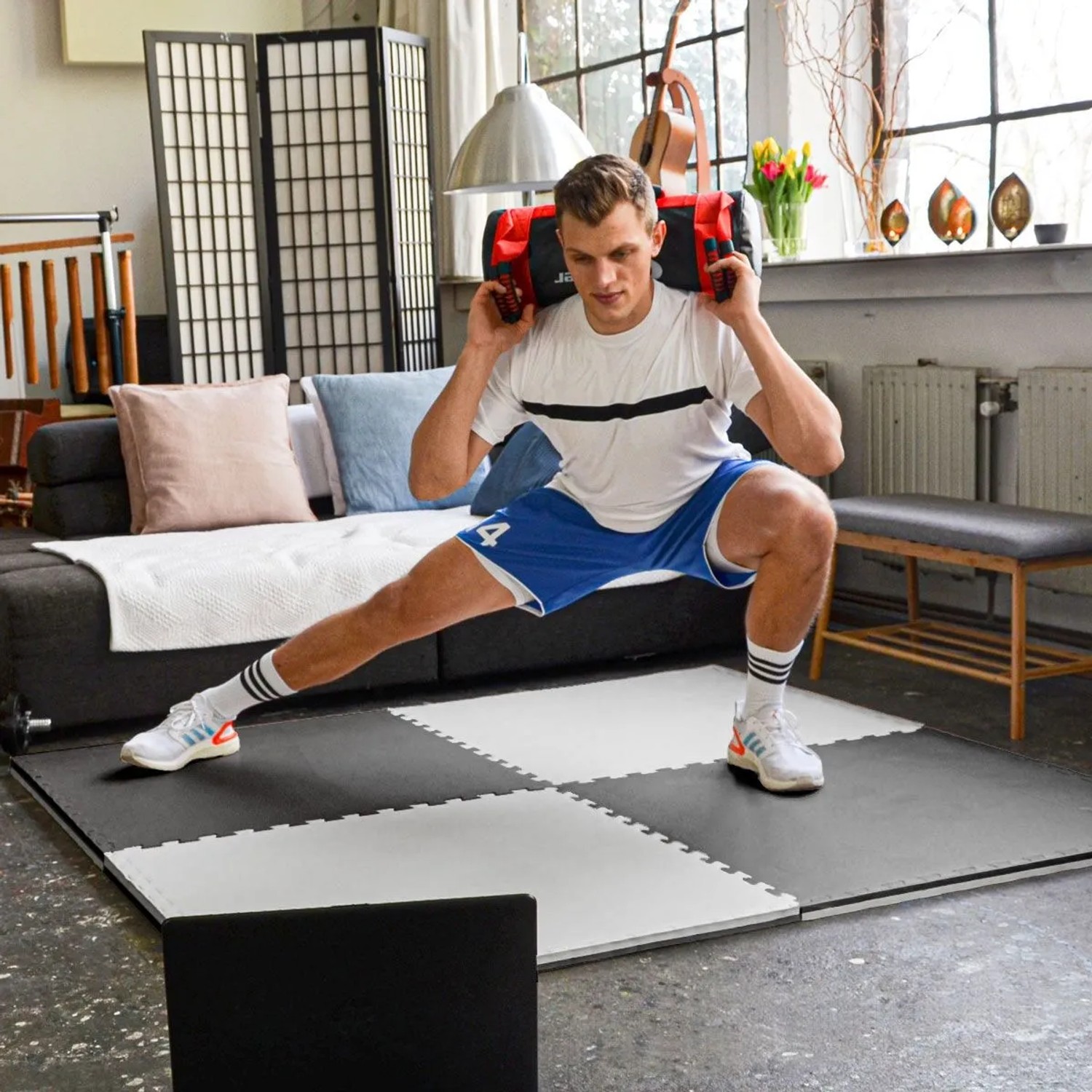 Mann trainiert auf eyepower Fitnessmatten (90x90x2cm) in Schwarz-Weiß im Wohnzimmer. Ideal für Home Gym & Bodenschutz.