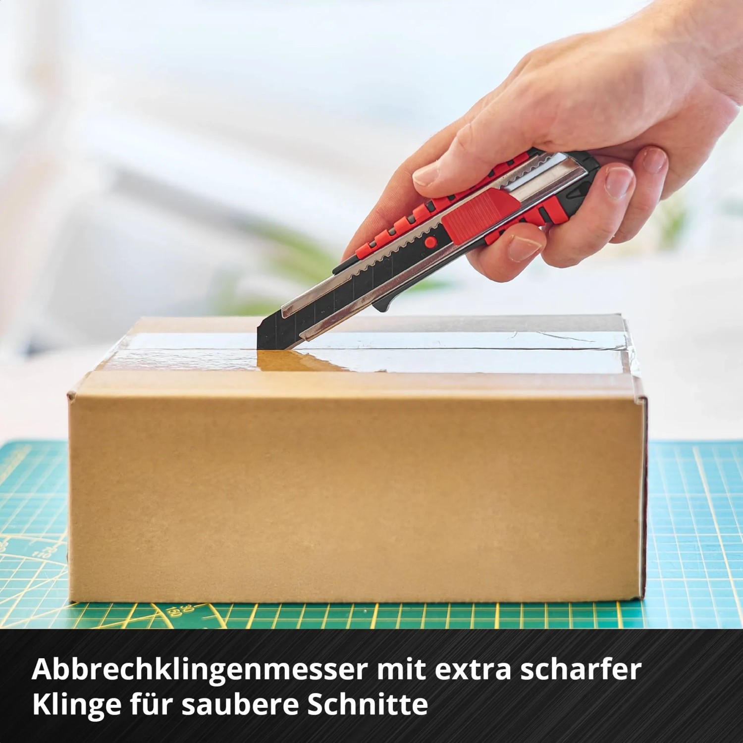 Hand öffnet Karton mit Einhell Werkzeugkoffer Abbrechklingenmesser. Werkzeug-Set.