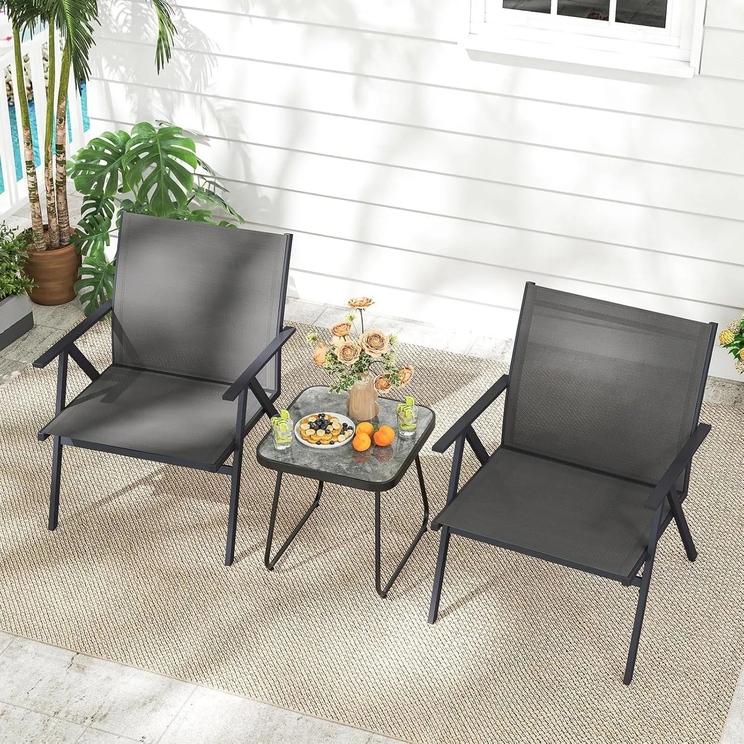 Zwei graue Gartenstühle mit breiter Sitzfläche und schwarzem Metallgestell auf einer Terrasse.