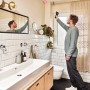 Mann misst mit Bosch AdvancedTemp Infrarot-Thermometer Temperatur im Badezimmer.
