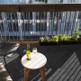 Anthrazitfarbener Primaflor Rasenteppich Park (1,33x5m) auf einem Balkon mit Tisch und Stuhl.