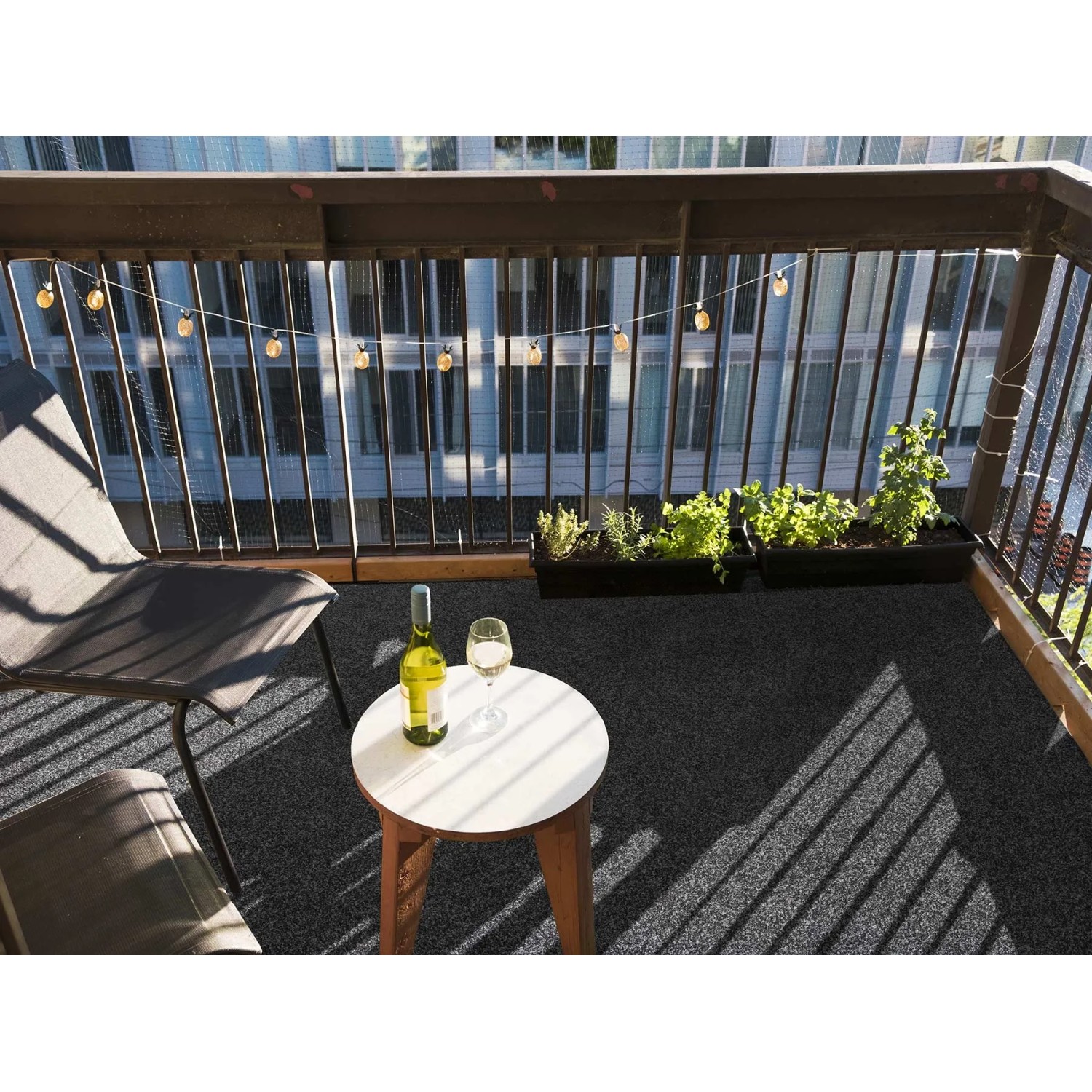 Anthrazitfarbener Primaflor Rasenteppich Park (1,33x5m) auf einem Balkon mit Tisch und Stuhl.