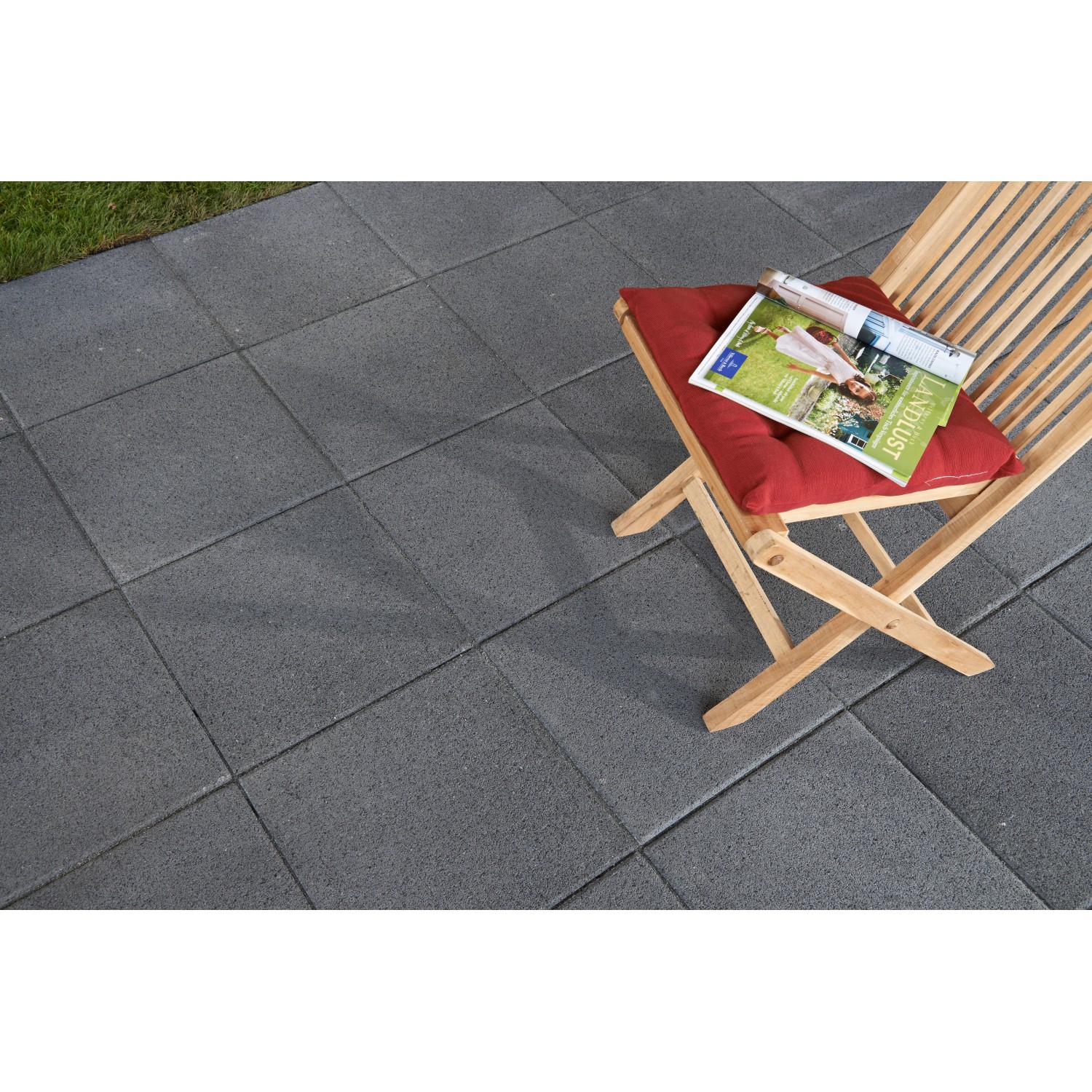 EHL Terrassenplatte Intotrend Aqua Anthrazit 40x40: Verlegte Betonplatten mit Stuhl und Zeitschrift.
