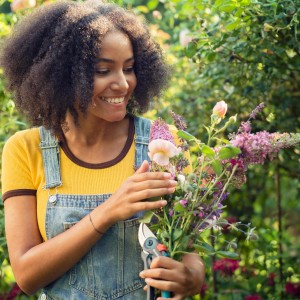 Frau schneidet Blumen mit Gardena ExpertCut Gartenschere.