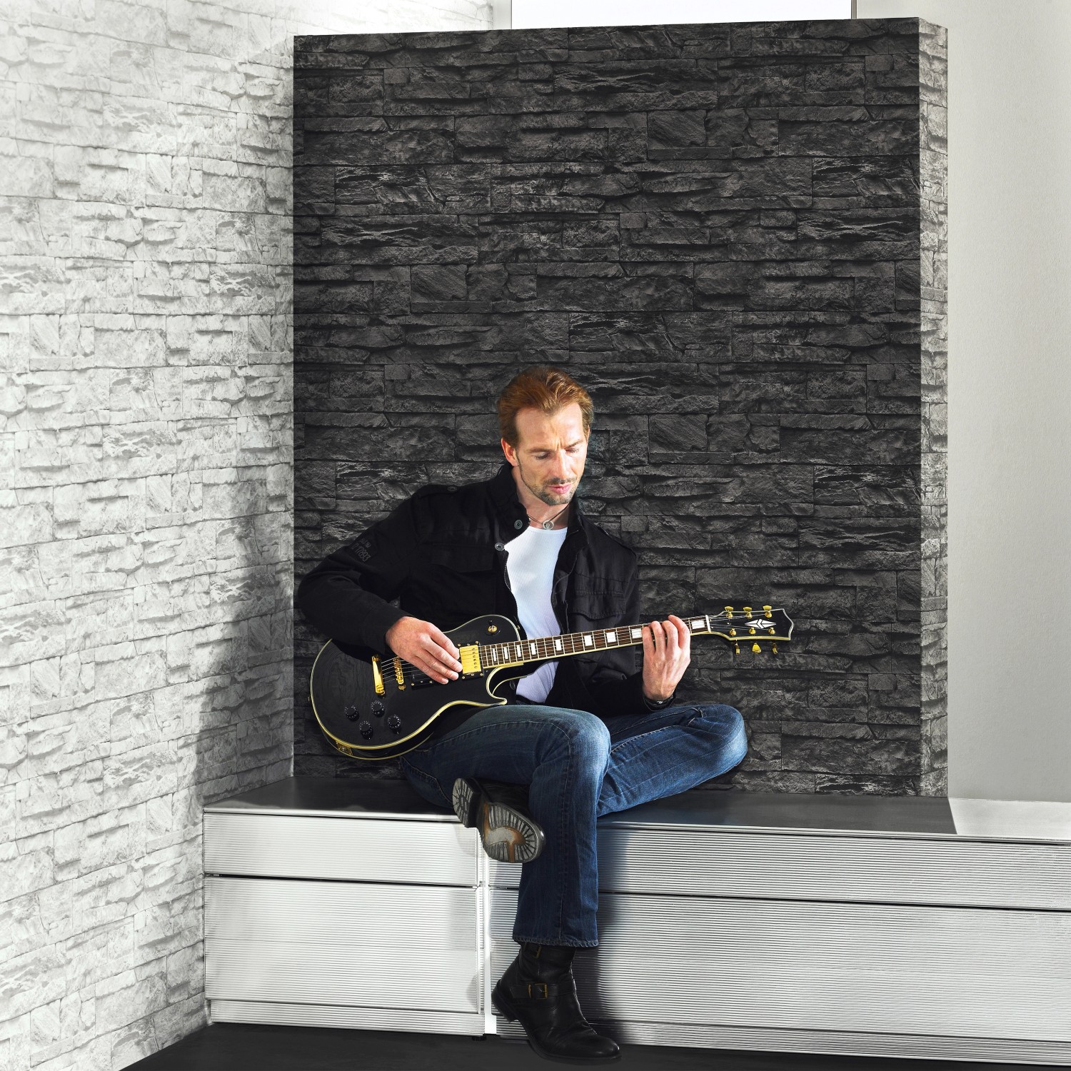 A.S. Creation Vliestapete Naturals Stein Schwarz: Wandgestaltung mit Steinoptik imitiert durch eine Person mit Gitarre.
