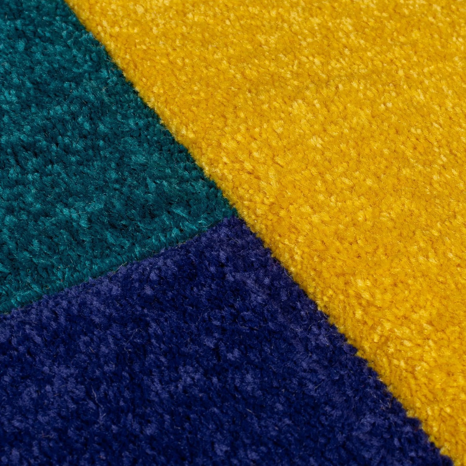 Nahaufnahme des Flair Rugs Kinderteppich Mambo. Geometrische Blöcke in Gelb, Petrol und Dunkelblau. Strapazierfähiger Polypropylen-Teppich.