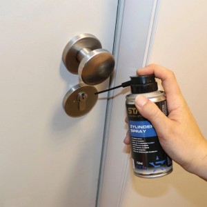 Hand sprüht Staloc Zylinder-Spray 150 ml in ein mechanisches Türschloss. Pflegespray für leichtgängige Schließzylinder.