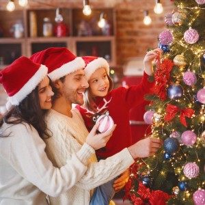 Familie schmückt Weihnachtsbaum mit rosa, matt, glänzend und glitzernden Kunststoff-Weihnachtskugeln aus 101er Set.