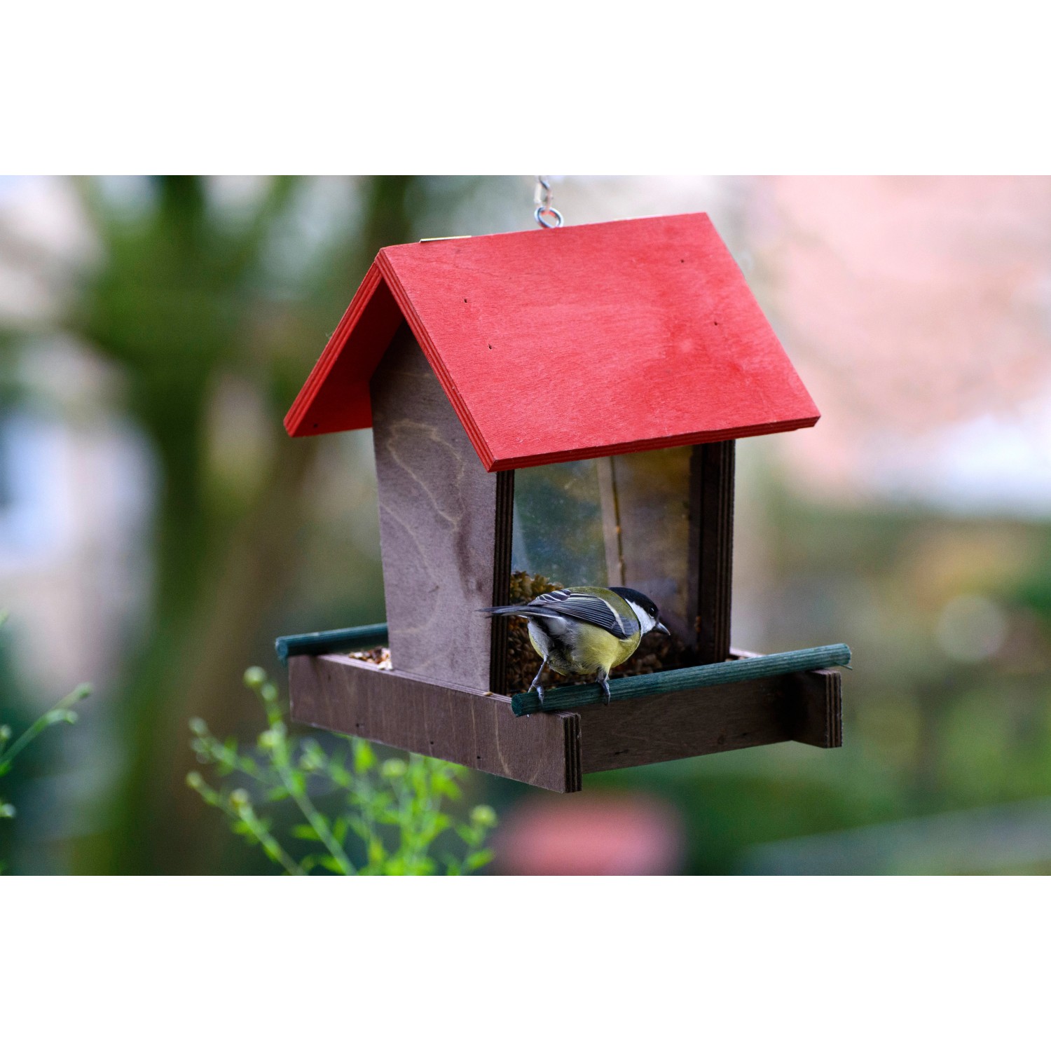 Dobar Vogelhaus mit rotem Dach und Meise am Futterspender.