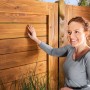Holzzaun mit Xyladecor Holzschutz-Lasur Plus Farblos behandelt. Frau berührt den Zaun.