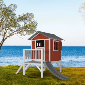 Axi Lodge XL Spielhaus in skandinavischem Rot mit grauer Rutsche vor blauem Gewässer.