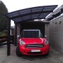Schwarzes Ximax Alu Carport Portoforte Typ 60 mit rotem Auto. Einzelcarport mit Carbonat-Dachplatten.