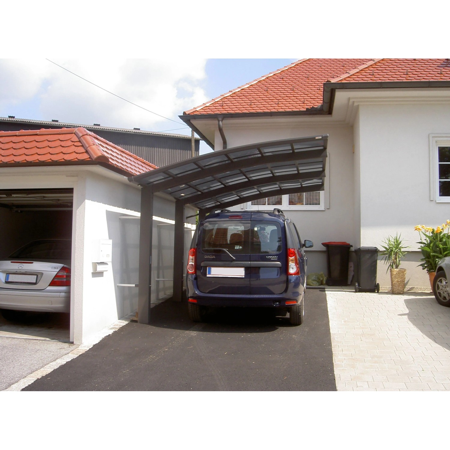 Schwarzer Ximax Alu Carport Portoforte Typ 110 XL mit Auto vor Haus.