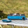 Campingaz Camp Bistro DLX Tischkocher (2.200 W) auf Campingtisch mit Geschirr.