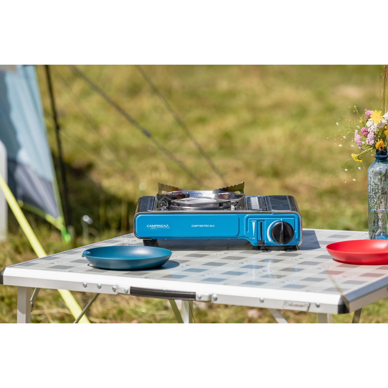 Campingaz Camp Bistro DLX Tischkocher (2.200 W) auf Campingtisch mit Geschirr.