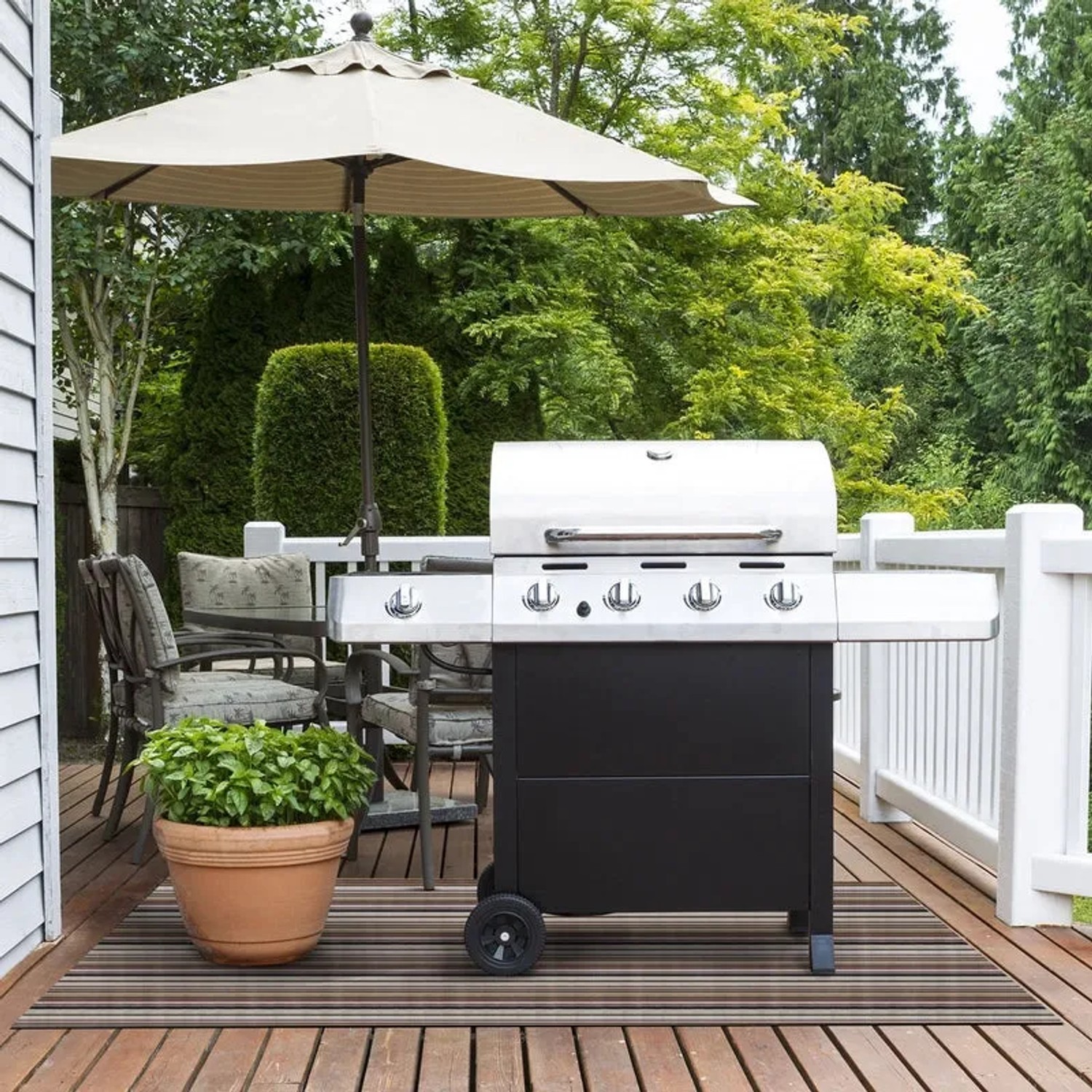 Gestreifter KARAT Outdoor Teppich Asti (180x300 cm) unter Grill auf Terrasse.