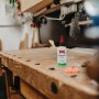 Ballistol Universalöl 100 ml Flasche mit rotem Verschluss auf rustikaler Holzwerkbank. Vielseitiges Öl für Pflege & Schutz.