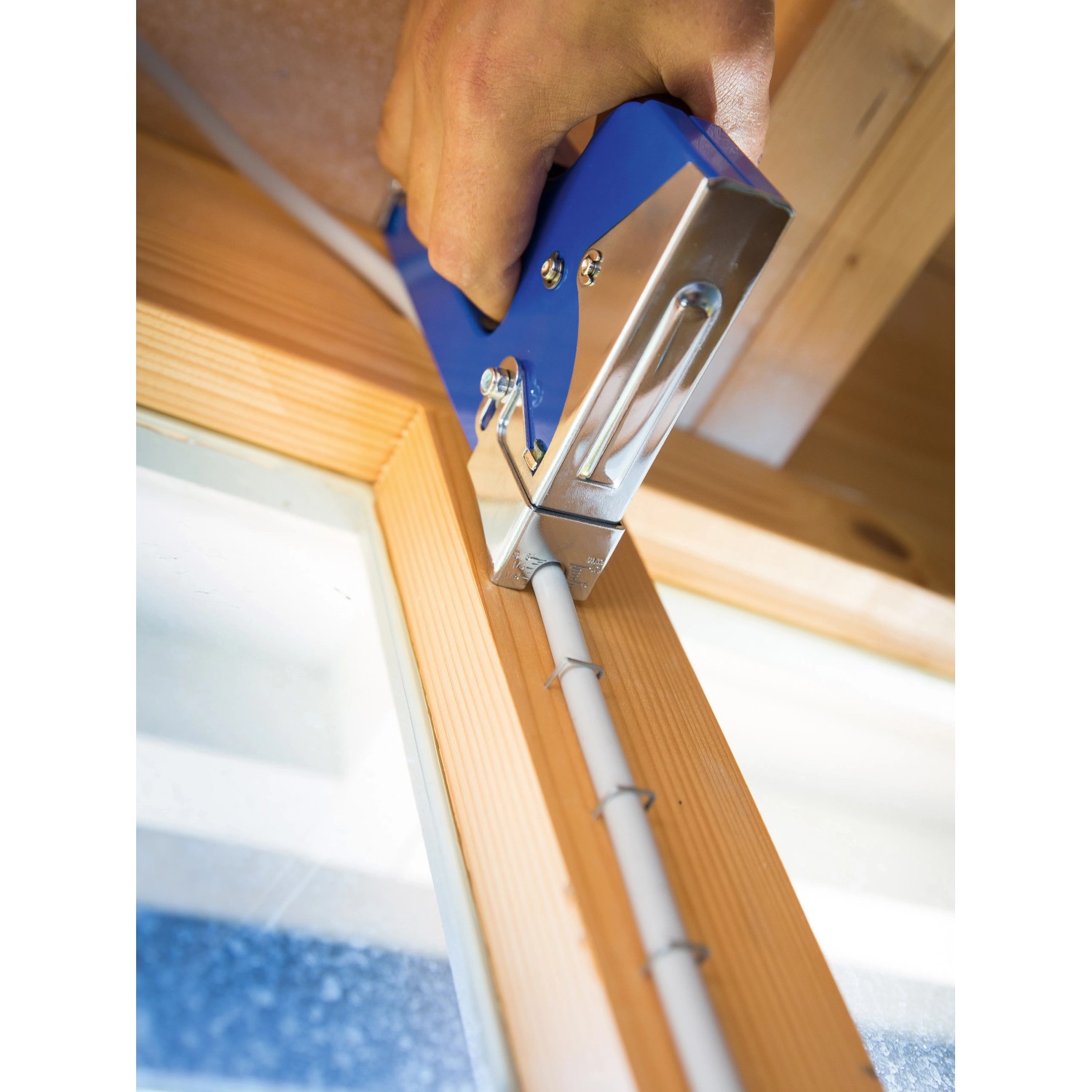 LUX Handtacker Classic beim Befestigen eines Kabels an einem Holzrahmen.