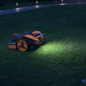 Worx Landroid Vision Mähroboter mit LED-Scheinwerfer im Einsatz bei Nacht.