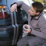 Mann klebt silbernes Tesa Extra Power Gewebeband auf ein Auto. Vielseitig einsetzbares Klebeband.