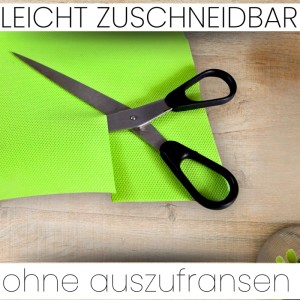 Apfelgrüne Sensalux Vlies-Tischdecke wird mit einer Schere zugeschnitten.