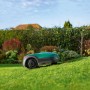 Robomow RK1000 Mähroboter auf Rasen vor Gartenhecke. Rasenroboter für Flächen bis 1.000 m².