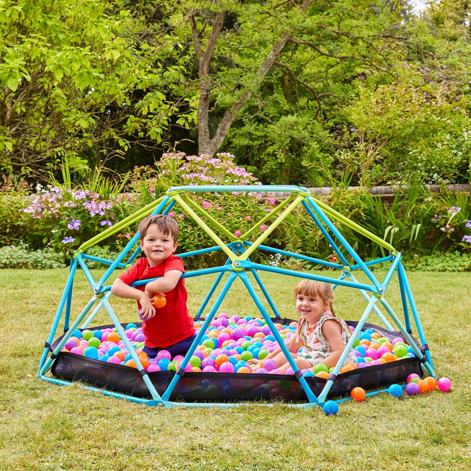 Blaues TP Toys Klettergerüst Metal Dome mit Kindern und Bällebad im Garten, 188x188x78 cm.
