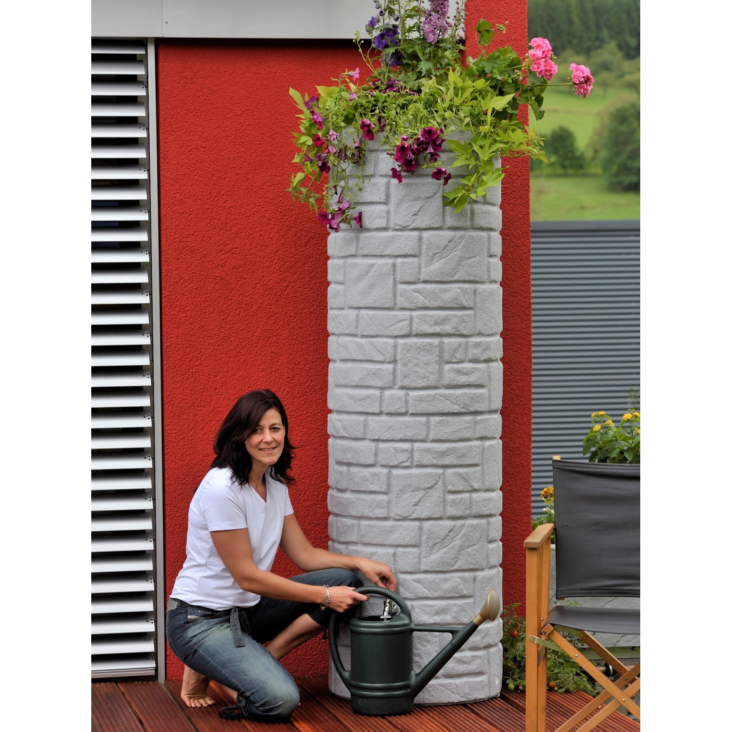 Arves Regentonne Arcado 460 l Granit mit Bepflanzung und Frau mit Gießkanne.