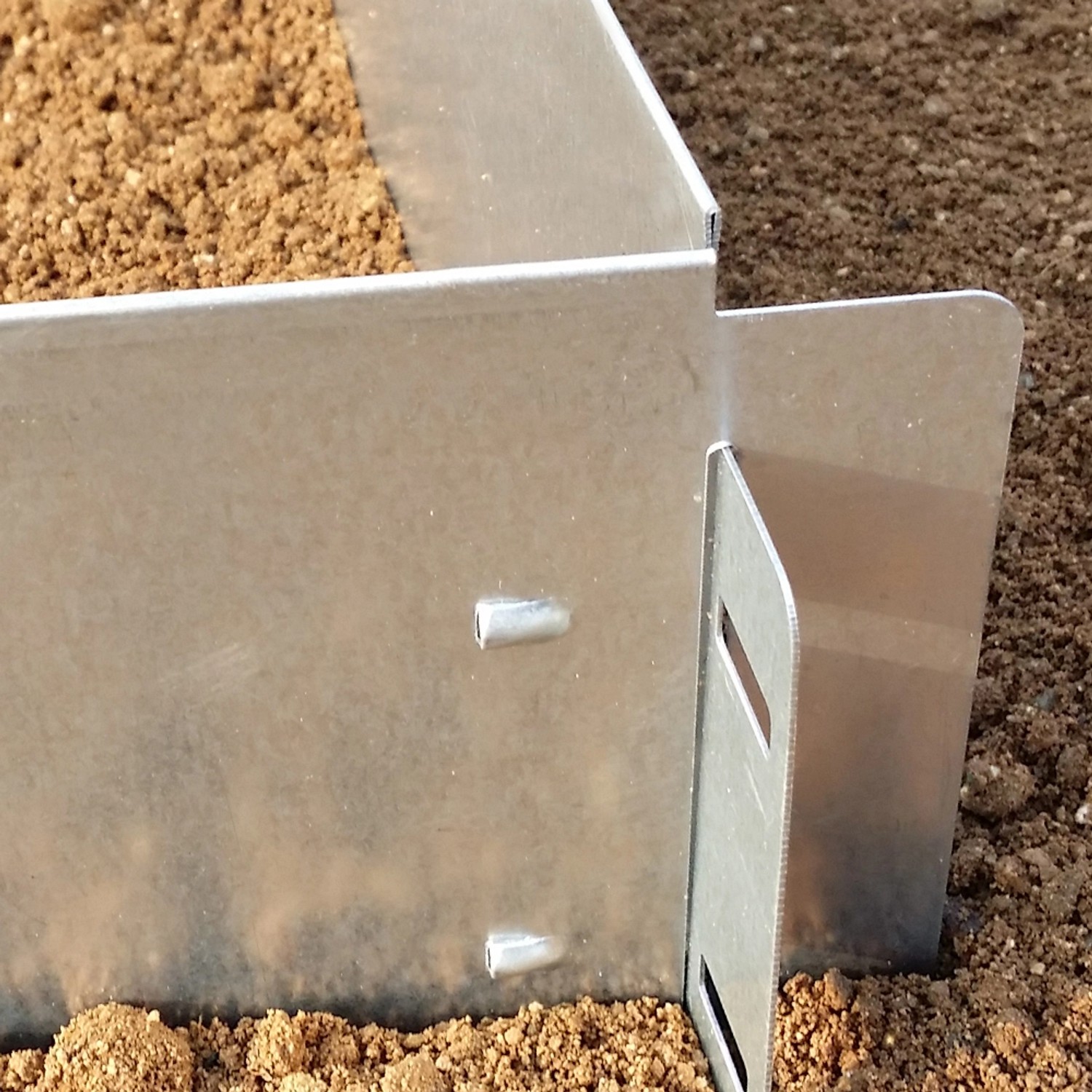 Detailaufnahme: Silberne OK-Living Rasenkante aus Metall, verbunden im Gartenbeet.